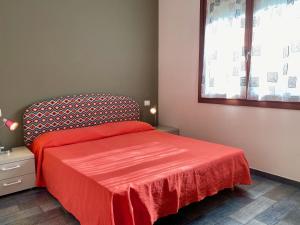 圣温琴佐Appartamento Giulia的一间卧室配有一张带红色床罩的床和窗户