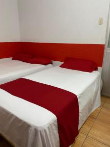 波托维耶霍Hotel Paraiso的红色和白色的客房内的两张床