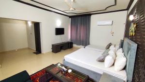 伊斯兰堡Aleph Islamabad Guest House的卧室配有白色的床和电视