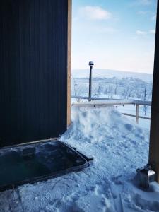基尔匹斯扎我维Aurora View Lapland, Sky View Bedroom & Jacuzzi的大楼旁的雪地里的一个热水浴缸