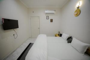 瓦拉纳西Stay Inn Kaashvi (A unit of Admire India Tourism Pvt. Ltd.)的白色卧室配有白色的床和电视