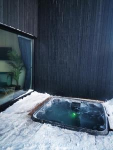 基尔匹斯扎我维Aurora View Lapland, Sky View Bedroom & Jacuzzi的大楼旁的雪覆盖的热水浴池