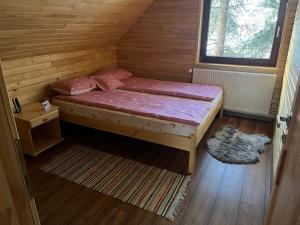 CiumaniKispatak Vendégház的木制客房的一张小床,设有窗户