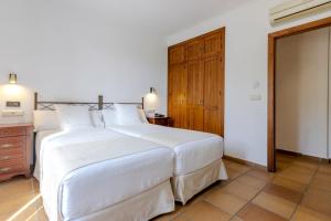 萨阿拉德洛斯阿图内斯Hostal La Muralla的卧室配有白色大床和木制橱柜