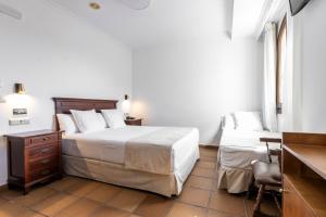 萨阿拉德洛斯阿图内斯Hostal La Muralla的一间卧室配有一张床、一张桌子和一把椅子