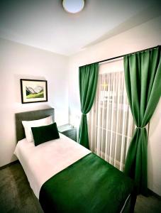 萨尔茨堡Hotel Genta的一间卧室配有一张带绿色窗帘的床和窗户。