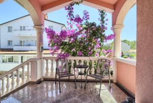 法扎纳Hotel Villa Vera 2的阳台配有两把椅子和紫色鲜花