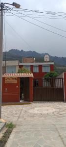 奇瓦伊Hospedaje Vacacional - Colca的一座红色的建筑,设有大门和栅栏