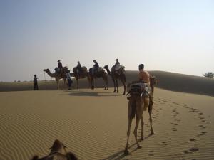 斋沙默尔Shahi Palace Hotel Jaisalmer的一群人在沙漠骑骆驼