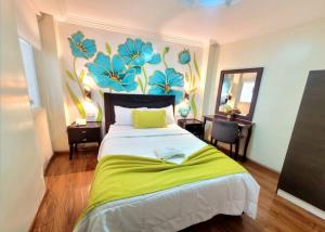 洛哈Hotel Virgen del Cisne的卧室配有一张挂着花壁画的床。