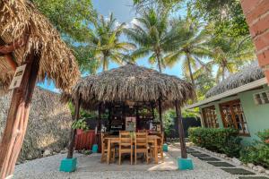 格兰德海滩Playa Grande Surf Camp的棕榈树草屋下的桌椅