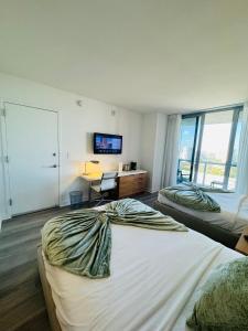 哈兰代尔海滩Lovely 2Bed 1Bath Condo With Private Balcony 18th Floor的一间卧室配有两张床、一张桌子和一台电视。