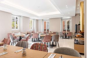 尼斯Hôtel Apollinaire Nice的用餐室设有桌椅和窗户。