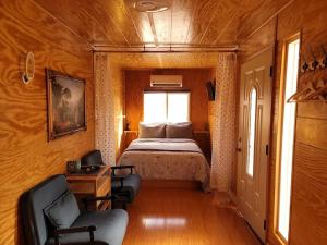 帕伦普Sun Tiny House A Pahrump的一间卧室配有一张床、两把椅子和一个窗户