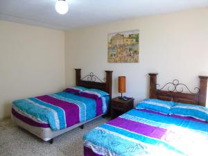 危地马拉Hostal Los Volcanes的卧室配有两张床,墙上挂着一幅画