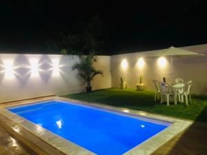 卡波布里奥Casa com piscina exclusiva的游泳池在晚上配有桌椅