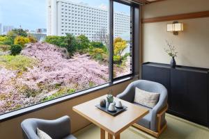 东京高轮花香路旅馆的客房设有两把椅子、一张桌子和大窗户