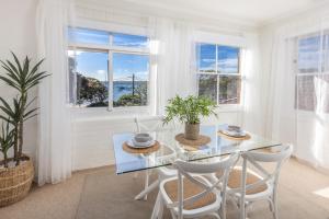 悉尼Luxe-Coastal Balmoral Beachfront Apartment的白色的用餐室配有玻璃桌和椅子