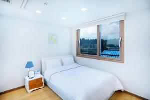 西归浦市The Naeun Stay的白色的卧室设有床和窗户