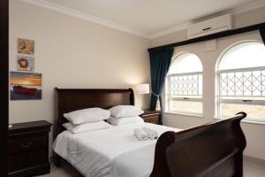 巴利托La Mustique 4的一间卧室配有一张带白色床单的床和两个窗户。
