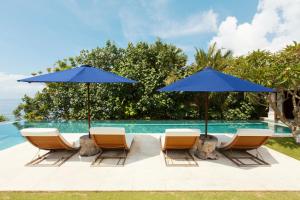 乌鲁瓦图乌干沙克利夫托普度假酒店的一组椅子和遮阳伞,位于游泳池旁
