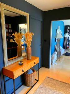 凯恩Appartement spacieux, calme et lumineux.的一间设有镜子的房间和一张带鲜花的桌子