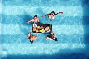 果阿旧城Elivaas Celest Luxe 4BHK Villa with Pvt Pool near Baga的一群人在游泳池里,拿着一盘食物