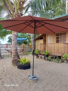 爱妮岛Kubo Inn & Beach Camp的房子前沙子里的红伞