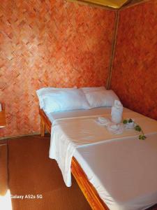 爱妮岛Kubo Inn & Beach Camp的一间小卧室,配有一张带白色床单的床