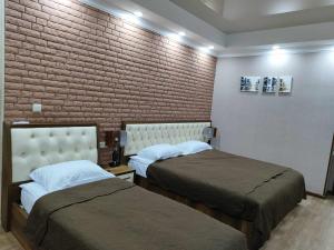 库塔伊西SULIKO Apartment的一间卧室设有两张床和砖墙
