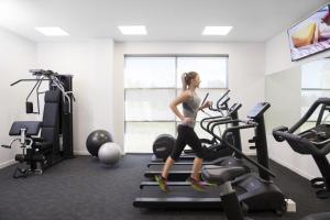 纽卡斯尔纽卡斯尔机场美居酒店的一名在健身房跑步机上跑步的女人