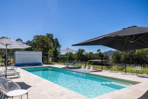 马奇'Bonnie View' A Magnificently Luxurious Retreat的一个带椅子和遮阳伞的游泳池