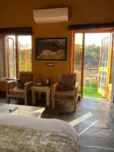达兰萨拉Prakriti Aalay - Riverside Mountain View Boutique Eco Resort的一间卧室配有一张床、两把椅子和一张桌子
