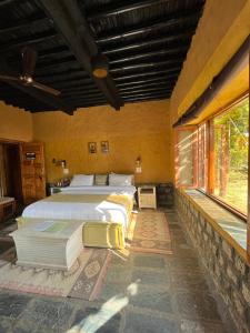 达兰萨拉Prakriti Aalay - Riverside Mountain View Boutique Eco Resort的一间卧室设有两张床和大窗户