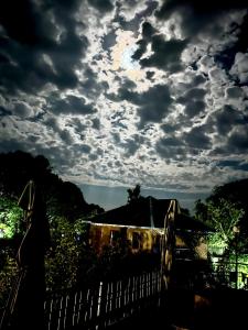 达兰萨拉Prakriti Aalay - Riverside Mountain View Boutique Eco Resort的阴云的天空,有房子和栅栏