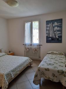切齐纳码头Giacomo Home的一间卧室设有两张床,窗户设有帆船