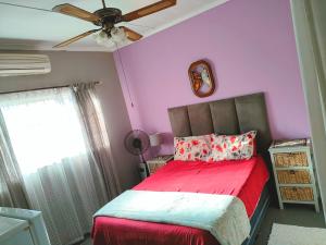 比勒陀利亚Accommodation@42 Capital的一间卧室配有一张红色的床和吊扇