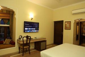 比卡内尔Heritage Resort Bikaner的一间卧室配有一张桌子和一台墙上的电视。
