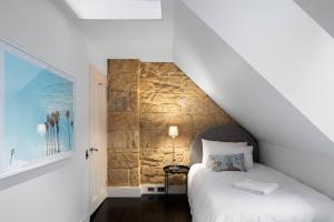 悉尼Elegant Paddington Sandstone Cottage with Parking的一间卧室设有一张床和石墙