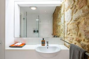 悉尼Elegant Paddington Sandstone Cottage with Parking的一间带水槽和石墙的浴室