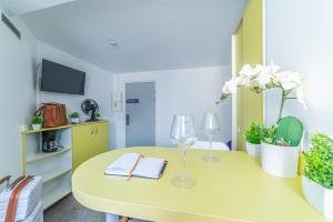 Courcouronnes蒙特珀埃夫里公寓式酒店的一张黄色桌子,上面放着两杯酒杯,还有书籍