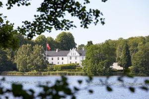SøndersøDallund Slot的一座大型白色房子,上面有国旗,上面有湖泊