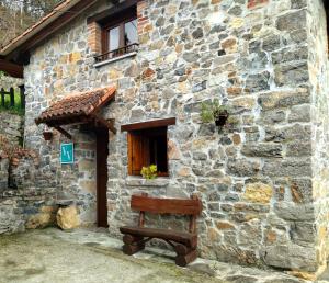坎加斯-德奥尼斯Casa Rural El Cotu en Cangas de Onís的石屋外的长凳