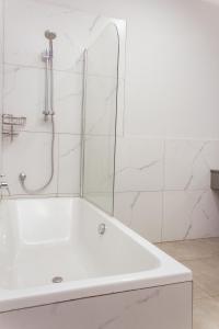 布兰太尔Cherrywood Estate Apartment的浴室铺有白色瓷砖,配有白色浴缸。