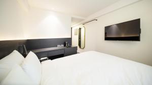 束草市Moyen Hotel的卧室配有白色的床和电视。