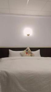 Wenquan知本喻禾溫泉民宿的卧室配有白色床和天花板上的灯