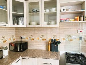 纳库鲁3 Bedroom Laneens Nest的厨房配有白色橱柜和黑微波炉
