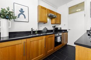 伦敦1 Bedroom Apartment - Mayfair (6)的厨房配有木制橱柜和黑色台面