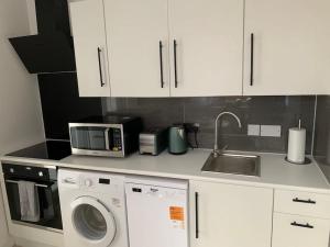 CarshaltonAnnex D. One Bedroom flat in south London的厨房配有微波炉、洗衣机和水槽。