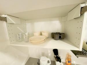 东京山手線恵比寿8分　4人可　的一间白色的厨房,在架子上摆放盘子和盘子
